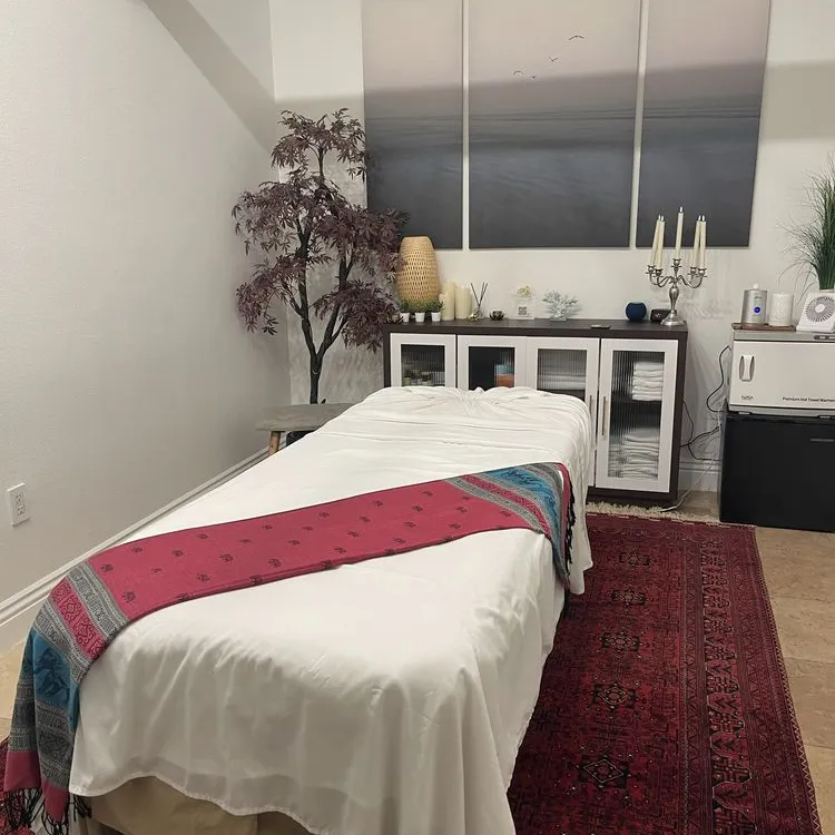 Note's treatment room, with a massage table on a red rug